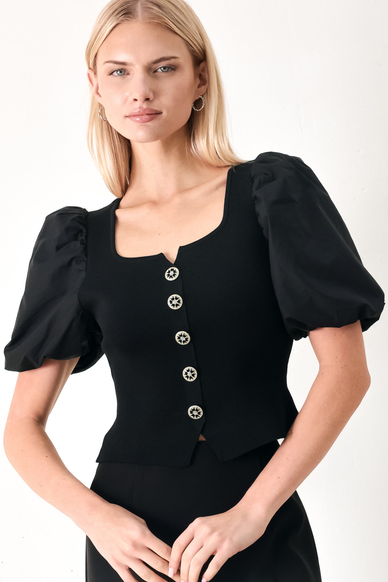 Woman wearing a black sweater knit top featuring square neckline, woven puff sleeve and front button detail | FREEMARKET