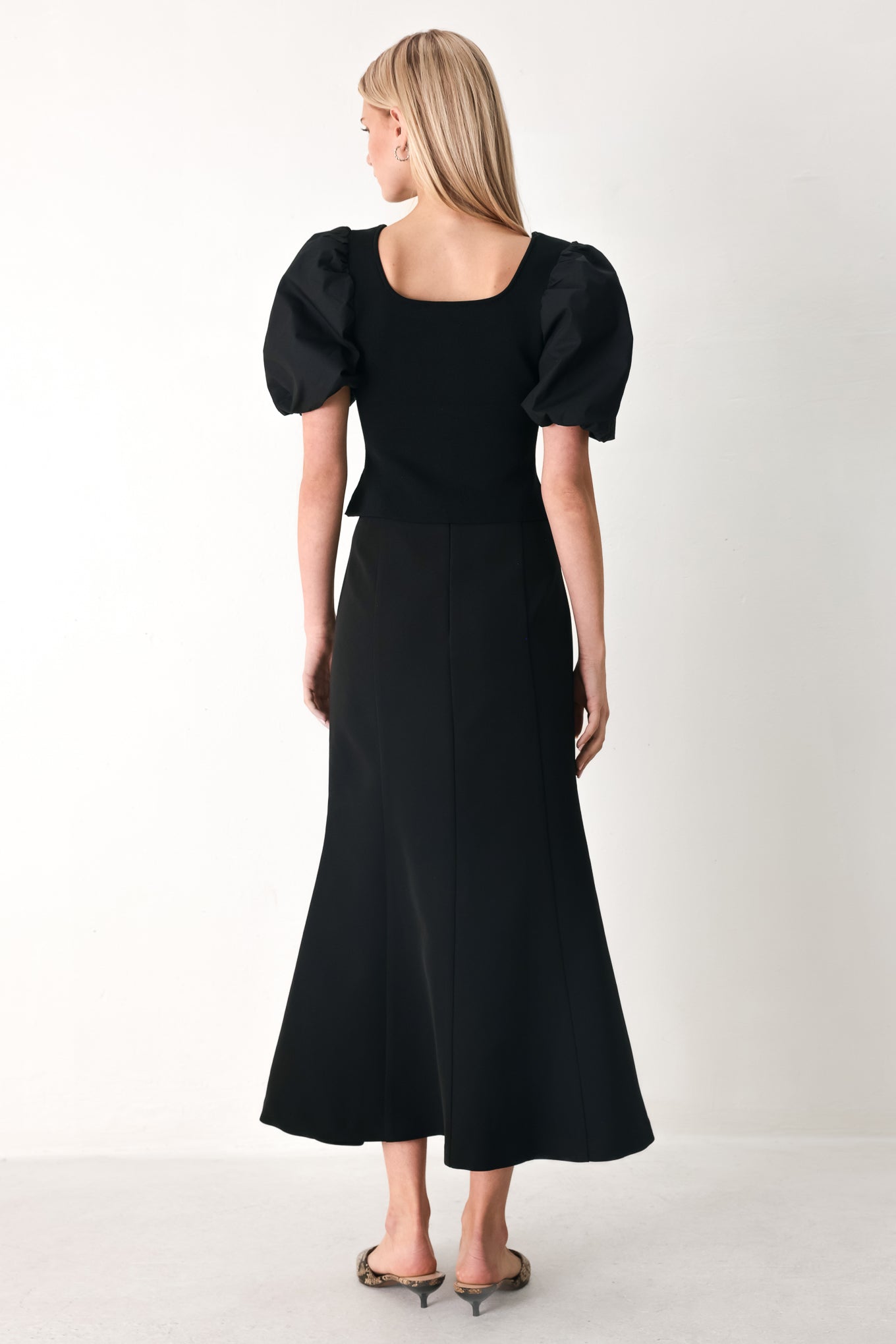 Woman wearing a black sweater knit top featuring square neckline, woven puff sleeve and front button detail | FREEMARKET
