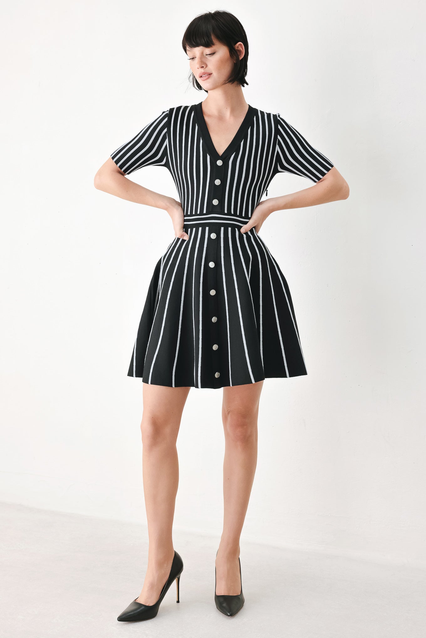 A woman modeling a short-sleeve V-neck dress with vertical black and silver stripes, a buttoned front, and a flared skirt | FREEMARKET