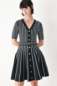 A woman modeling a short-sleeve V-neck dress with vertical black and silver stripes, a buttoned front, and a flared skirt | FREEMARKET