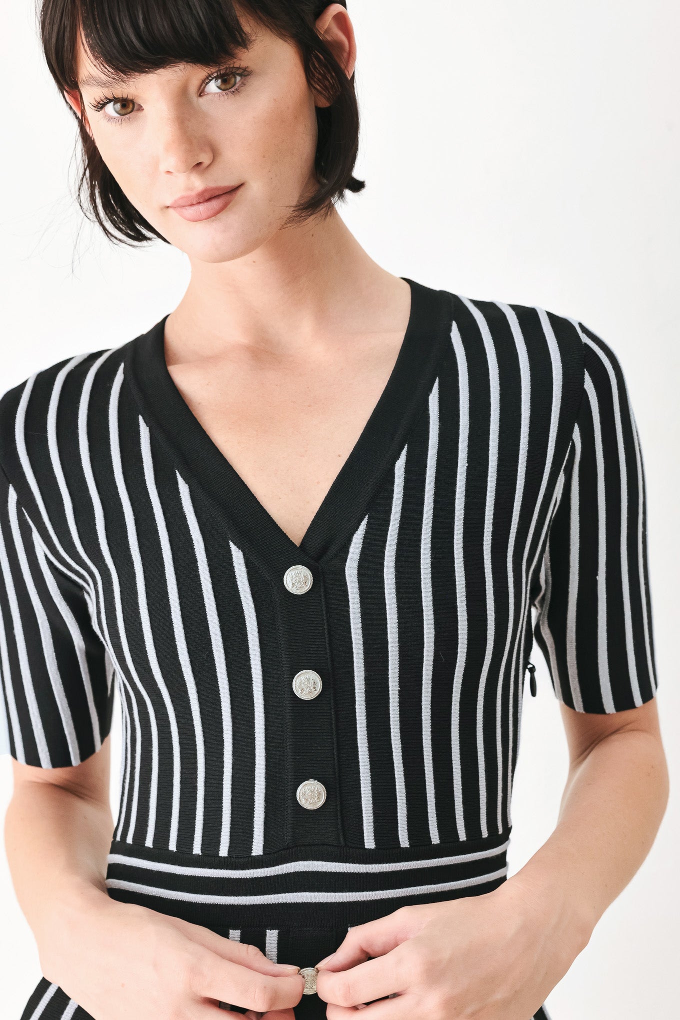 A woman modeling a short-sleeve V-neck dress with vertical black and silver stripes, a buttoned front, and a flared skirt | FREEMARKET