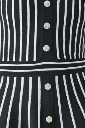 A woman modeling a short-sleeve V-neck dress with vertical black and silver stripes, a buttoned front, and a flared skirt | FREEMARKET