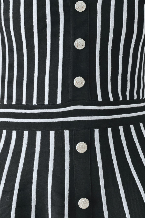 A woman modeling a short-sleeve V-neck dress with vertical black and silver stripes, a buttoned front, and a flared skirt | FREEMARKET
