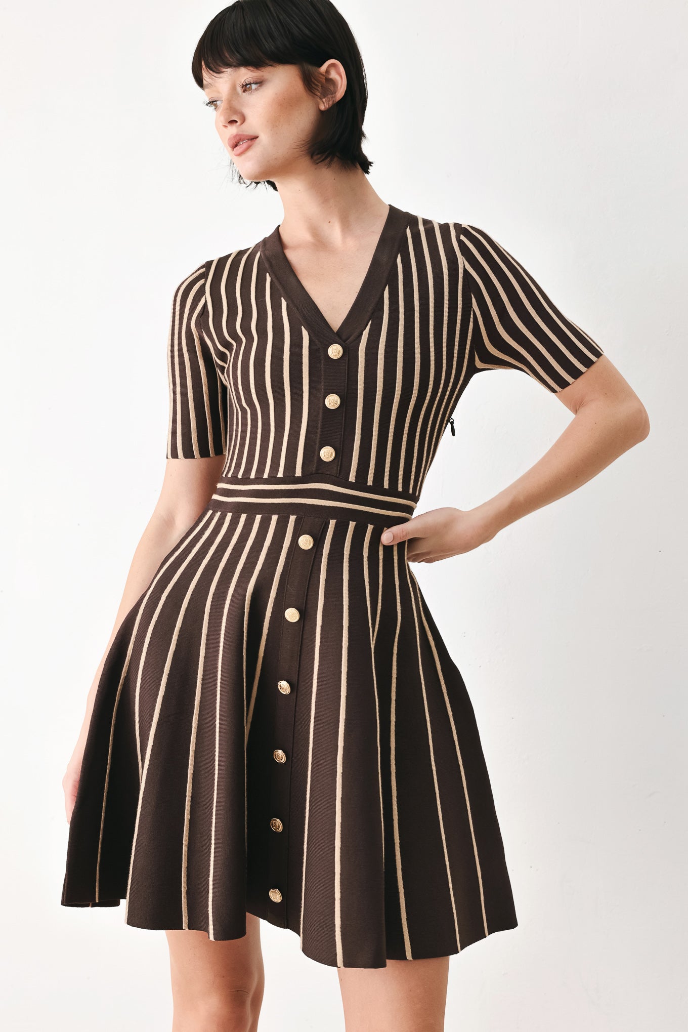 A woman modeling a short-sleeve V-neck dress with vertical brown and beige stripes, a buttoned front, and a flared skirt | FREEMARKET