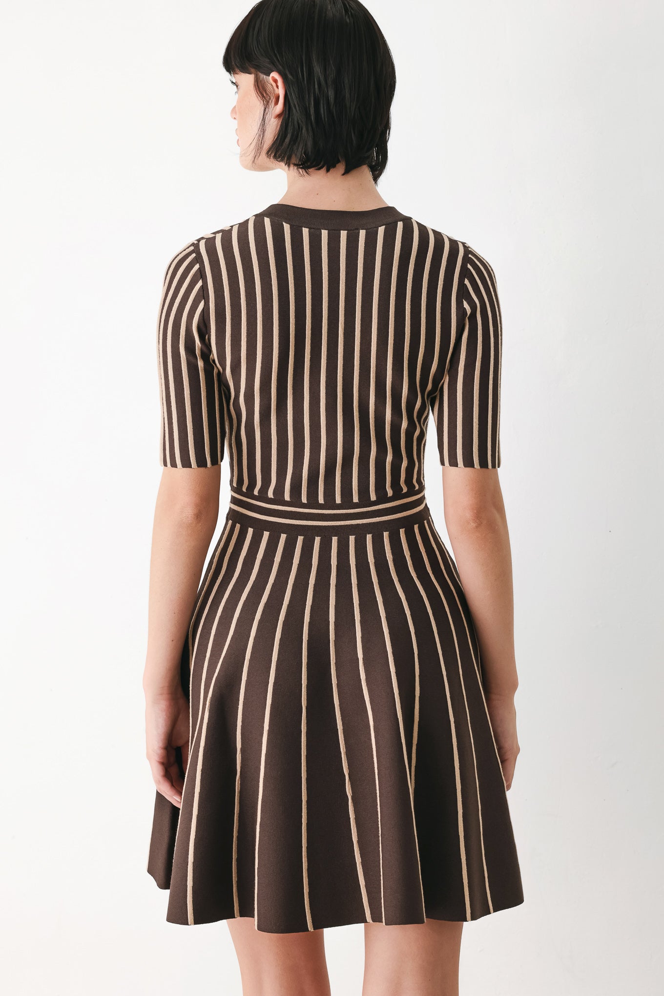 A woman modeling a short-sleeve V-neck dress with vertical brown and beige stripes, a buttoned front, and a flared skirt | FREEMARKET