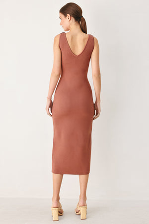 Woman wearing a clay colored sweater knit midi dress featuring V neckline and side cut out in a flower shape | FREEMARKET