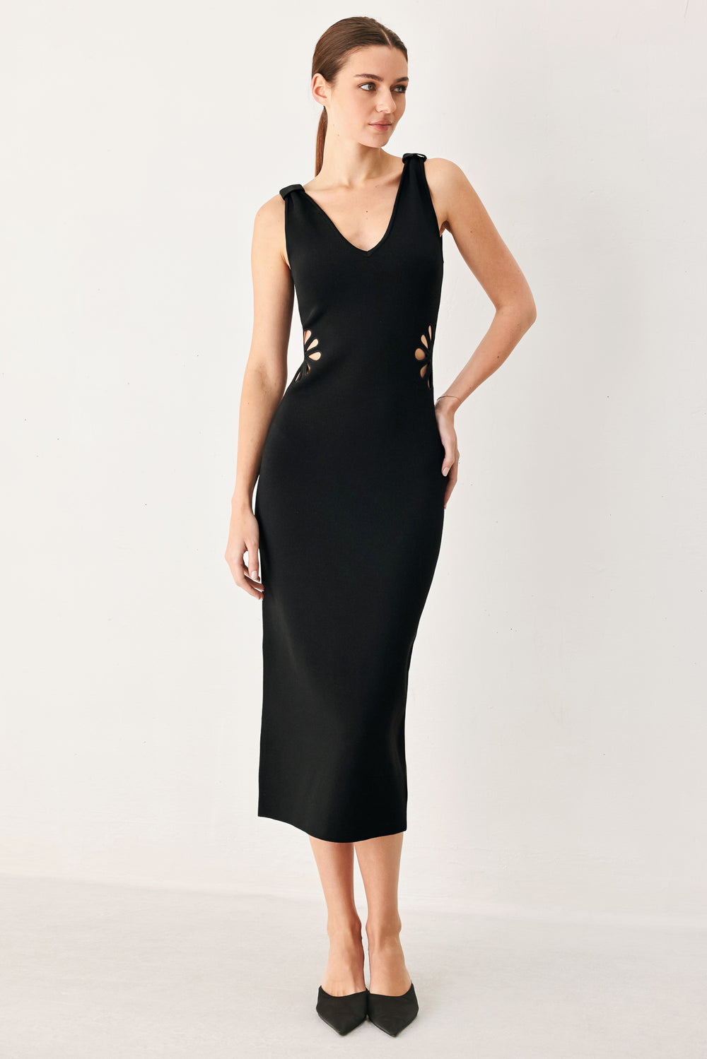 Woman wearing a black sweater knit midi dress featuring V neckline and side cut out in a flower shape | FREEMARKET