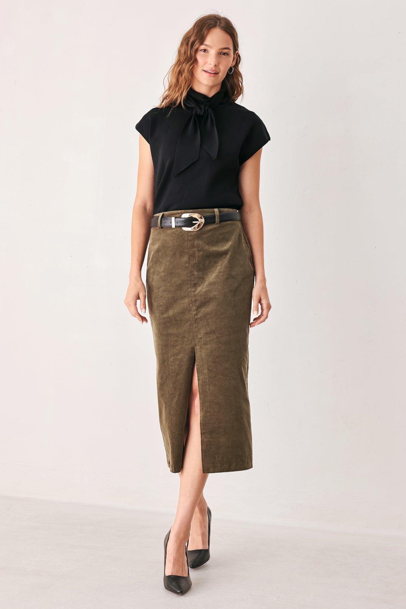 A woman wearing a black short-sleeve knit top with a high mock neck and a large draped tie detail at the front | FREEMARKET