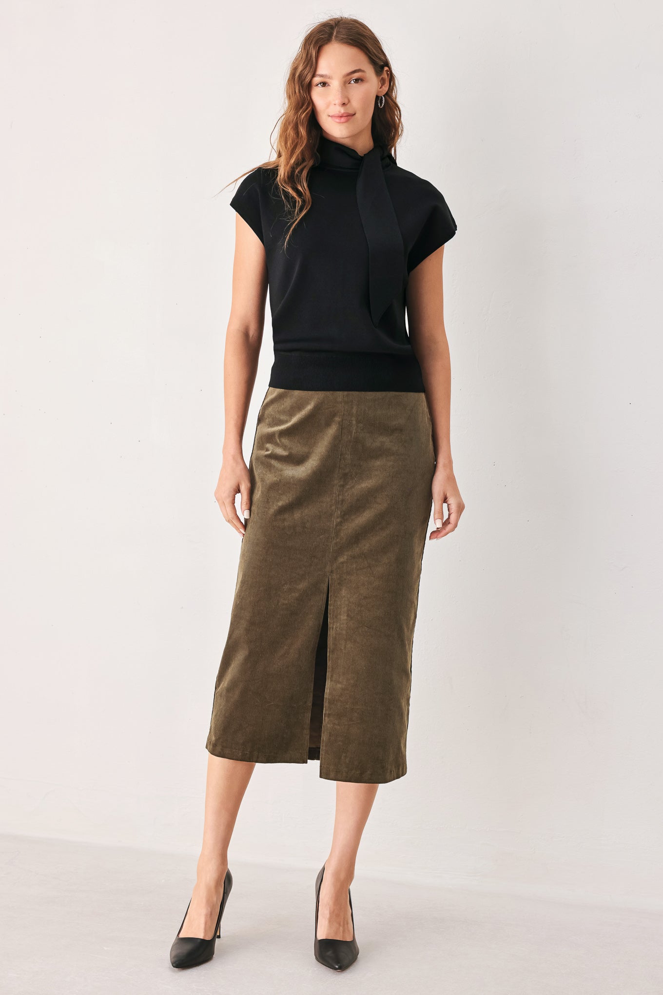 A woman wearing a black short-sleeve knit top with a high mock neck and a large draped tie detail at the front | FREEMARKET