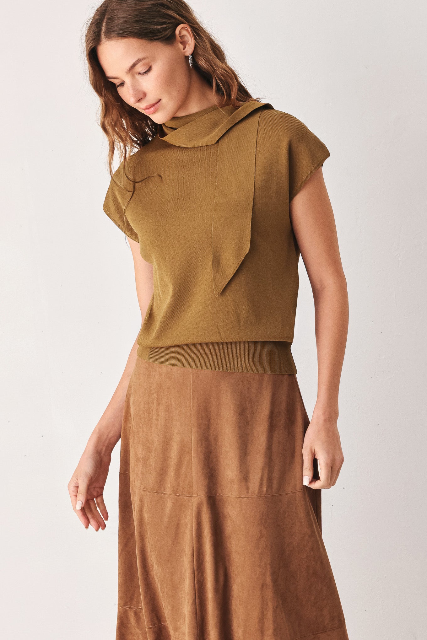 A woman wearing a camel short-sleeve knit top with a high mock neck and a large draped tie detail at the front | FREEMARKET