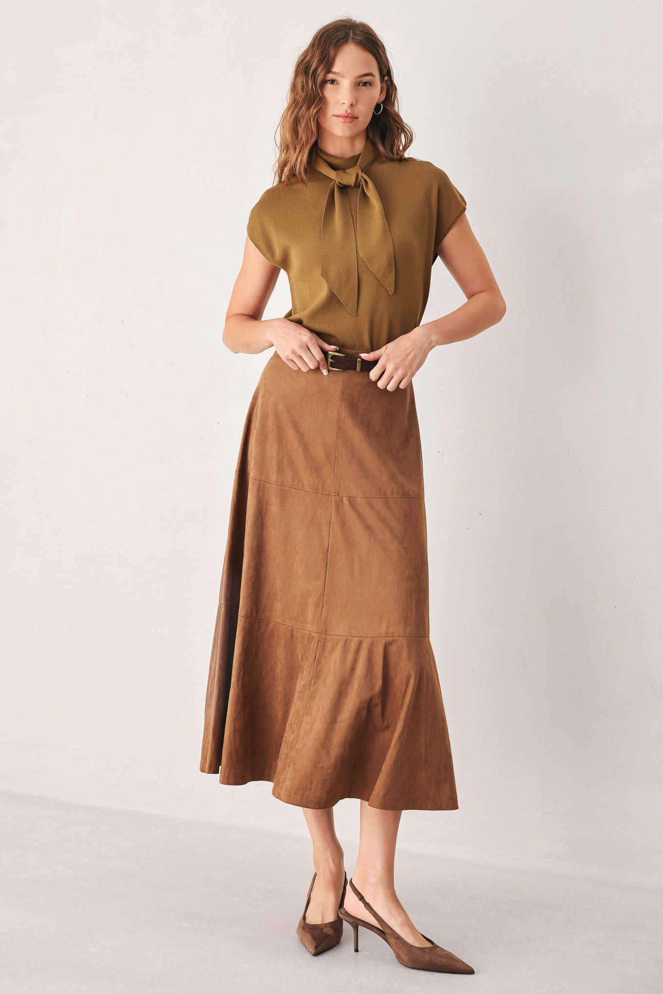 A woman wearing a camel short-sleeve knit top with a high mock neck and a large draped tie detail at the front | FREEMARKET