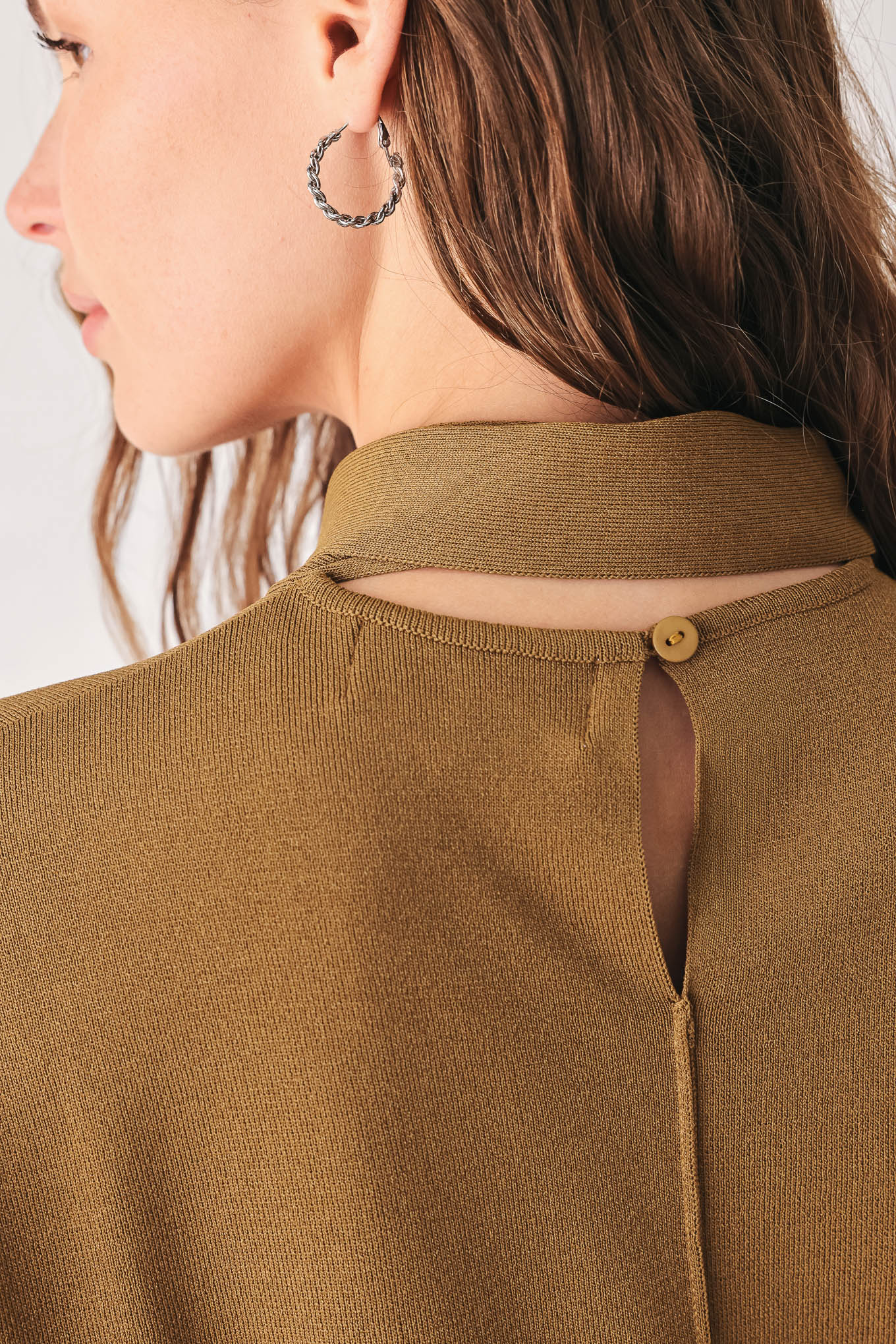 A woman wearing a camel short-sleeve knit top with a high mock neck and a large draped tie detail at the front | FREEMARKET