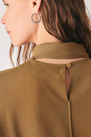 A woman wearing a camel short-sleeve knit top with a high mock neck and a large draped tie detail at the front | FREEMARKET