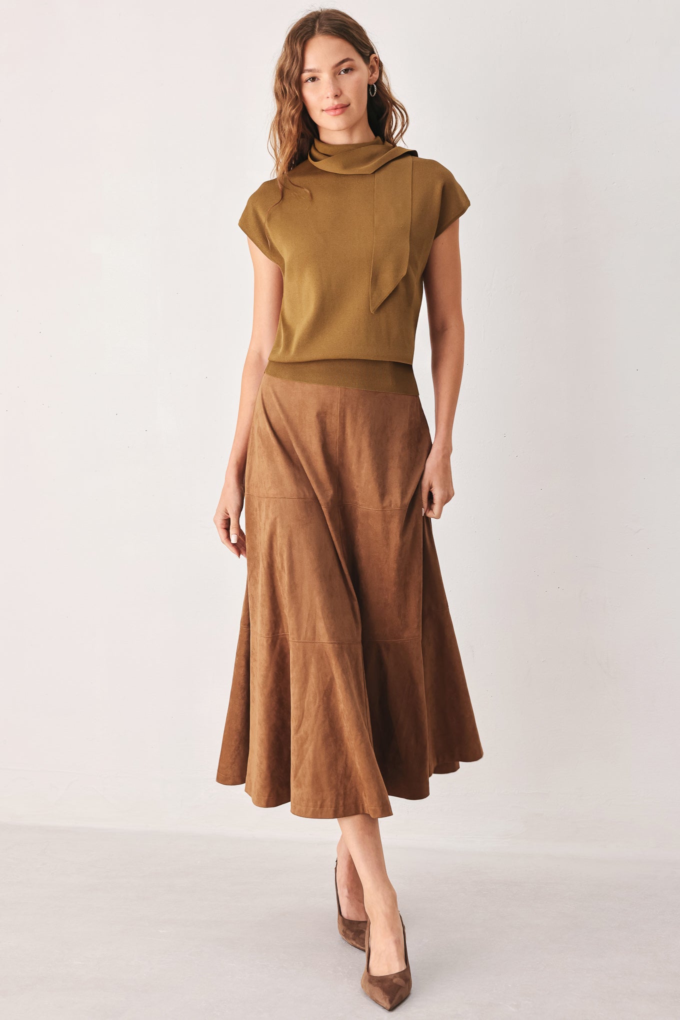 A woman wearing a camel short-sleeve knit top with a high mock neck and a large draped tie detail at the front | FREEMARKET