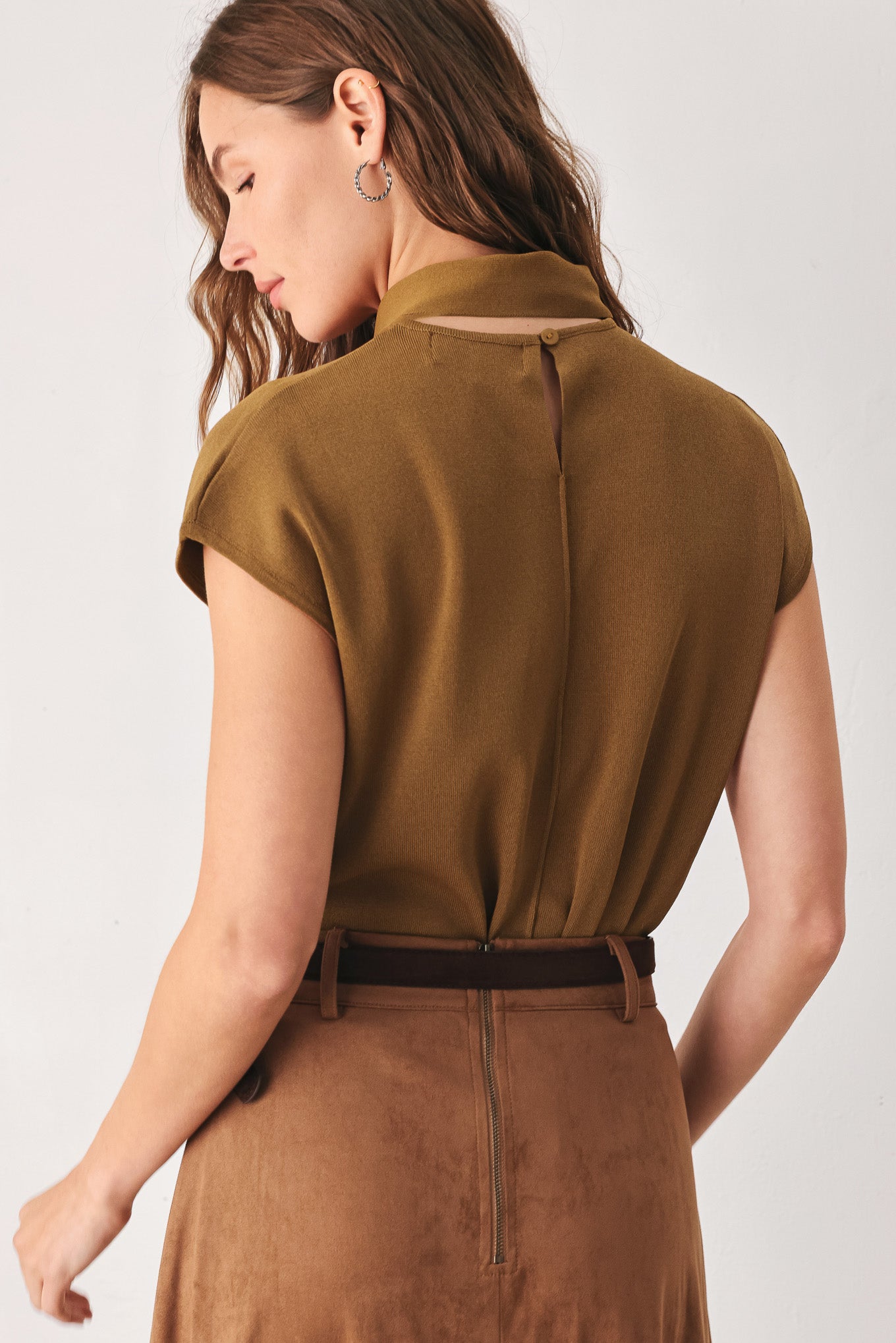 A woman wearing a camel short-sleeve knit top with a high mock neck and a large draped tie detail at the front | FREEMARKET
