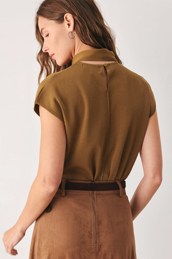 A woman wearing a camel short-sleeve knit top with a high mock neck and a large draped tie detail at the front | FREEMARKET