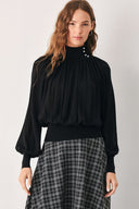 A woman wearing a black long-sleeve blouse with a high gathered neckline and pearl-like embellishments | FREEMARKET