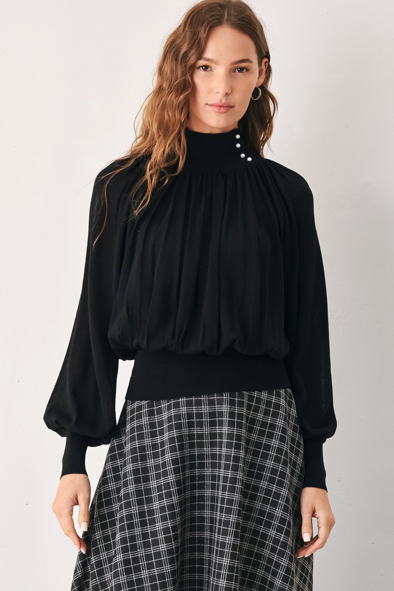 A woman wearing a black long-sleeve blouse with a high gathered neckline and pearl-like embellishments | FREEMARKET