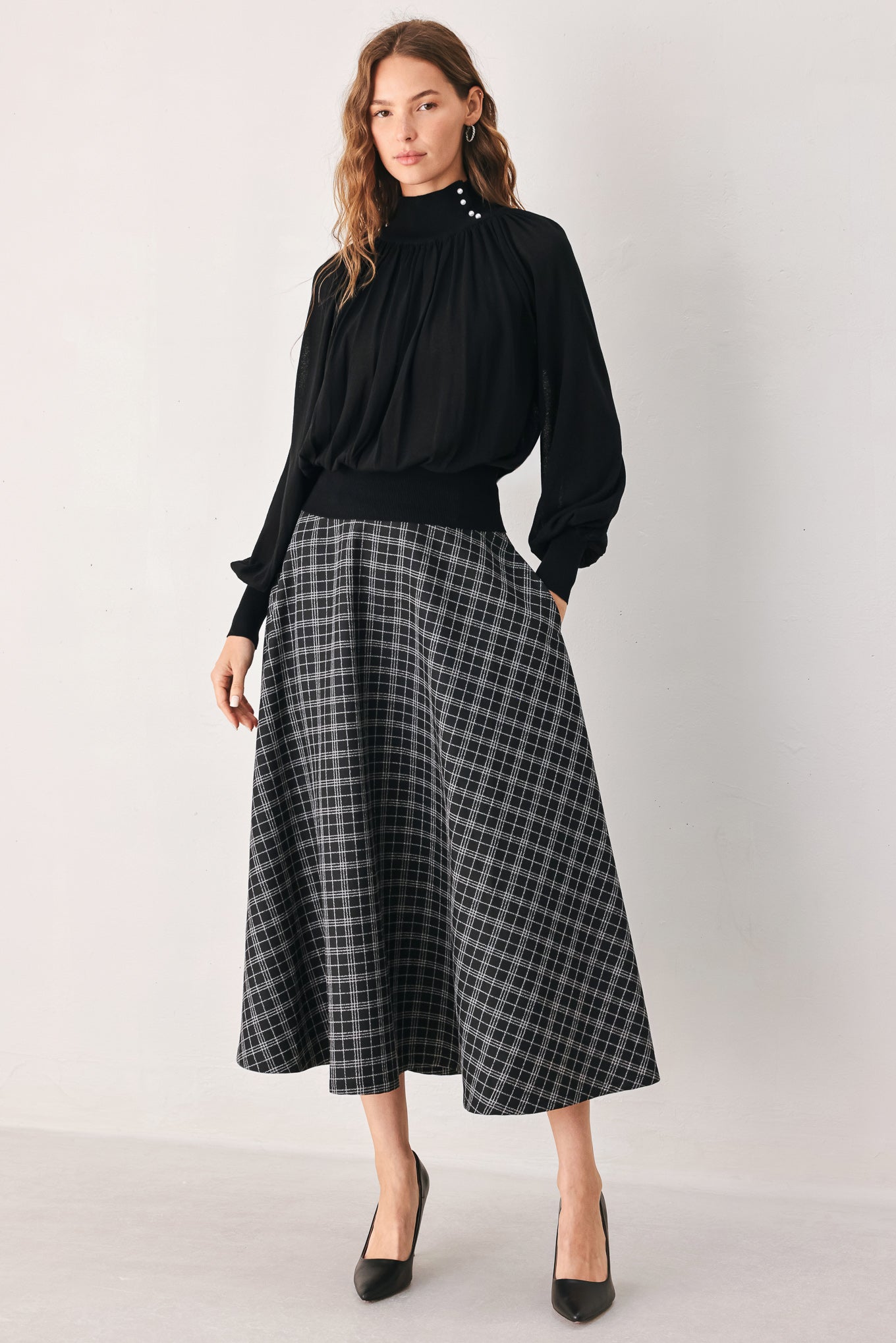 A woman wearing a black long-sleeve blouse with a high gathered neckline and pearl-like embellishments | FREEMARKET