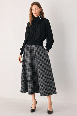 A woman wearing a black long-sleeve blouse with a high gathered neckline and pearl-like embellishments | FREEMARKET