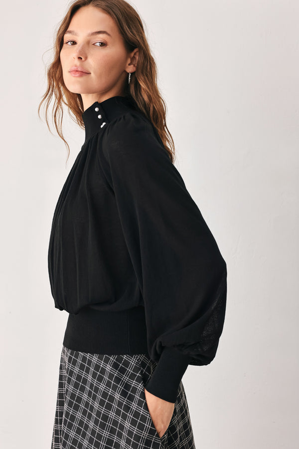 A woman wearing a black long-sleeve blouse with a high gathered neckline and pearl-like embellishments | FREEMARKET