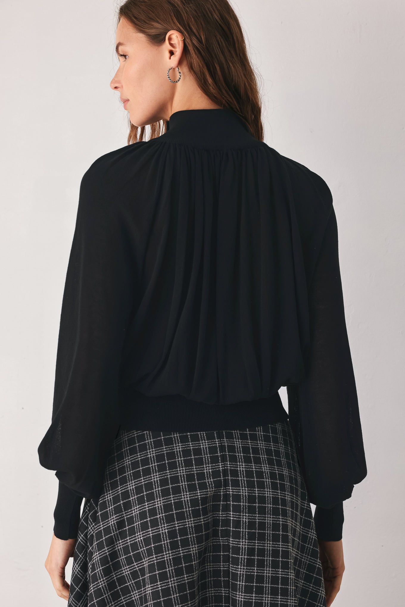 A woman wearing a black long-sleeve blouse with a high gathered neckline and pearl-like embellishments | FREEMARKET