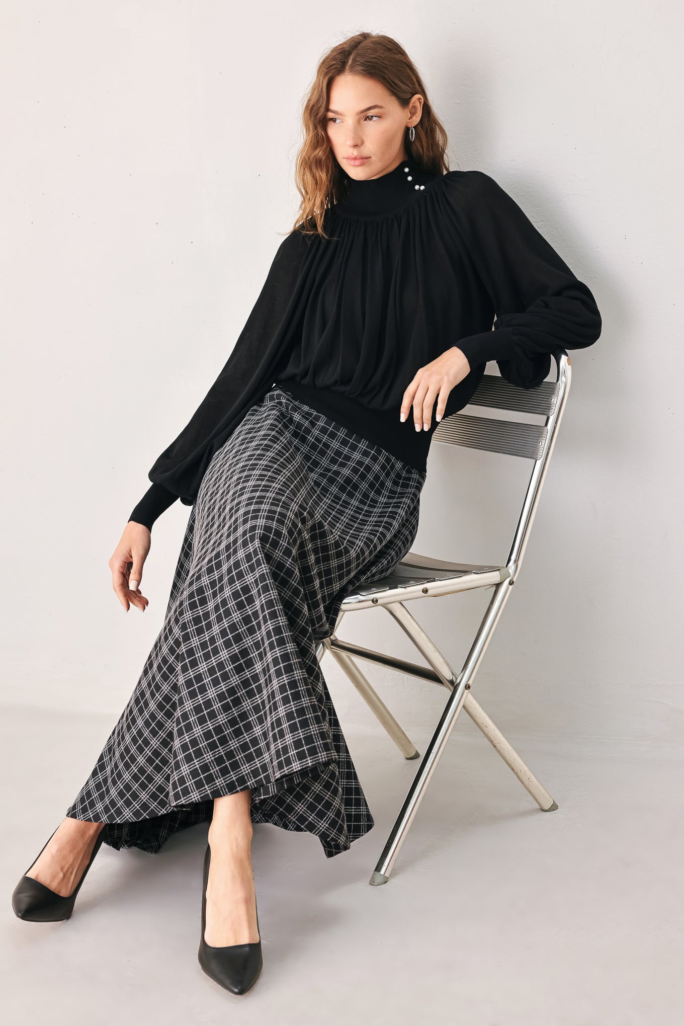 A woman wearing a black long-sleeve blouse with a high gathered neckline and pearl-like embellishments | FREEMARKET