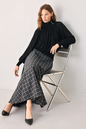 A woman wearing a black long-sleeve blouse with a high gathered neckline and pearl-like embellishments | FREEMARKET