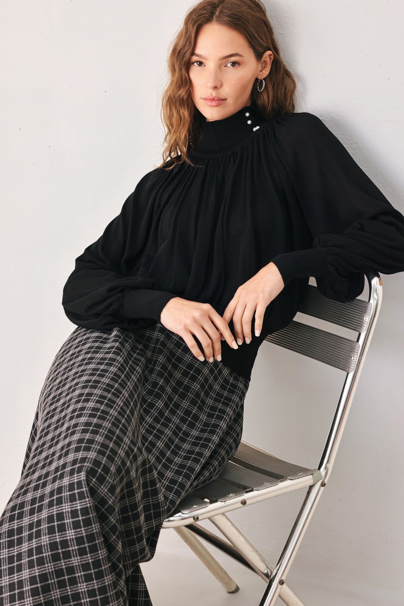 A woman wearing a black long-sleeve blouse with a high gathered neckline and pearl-like embellishments | FREEMARKET