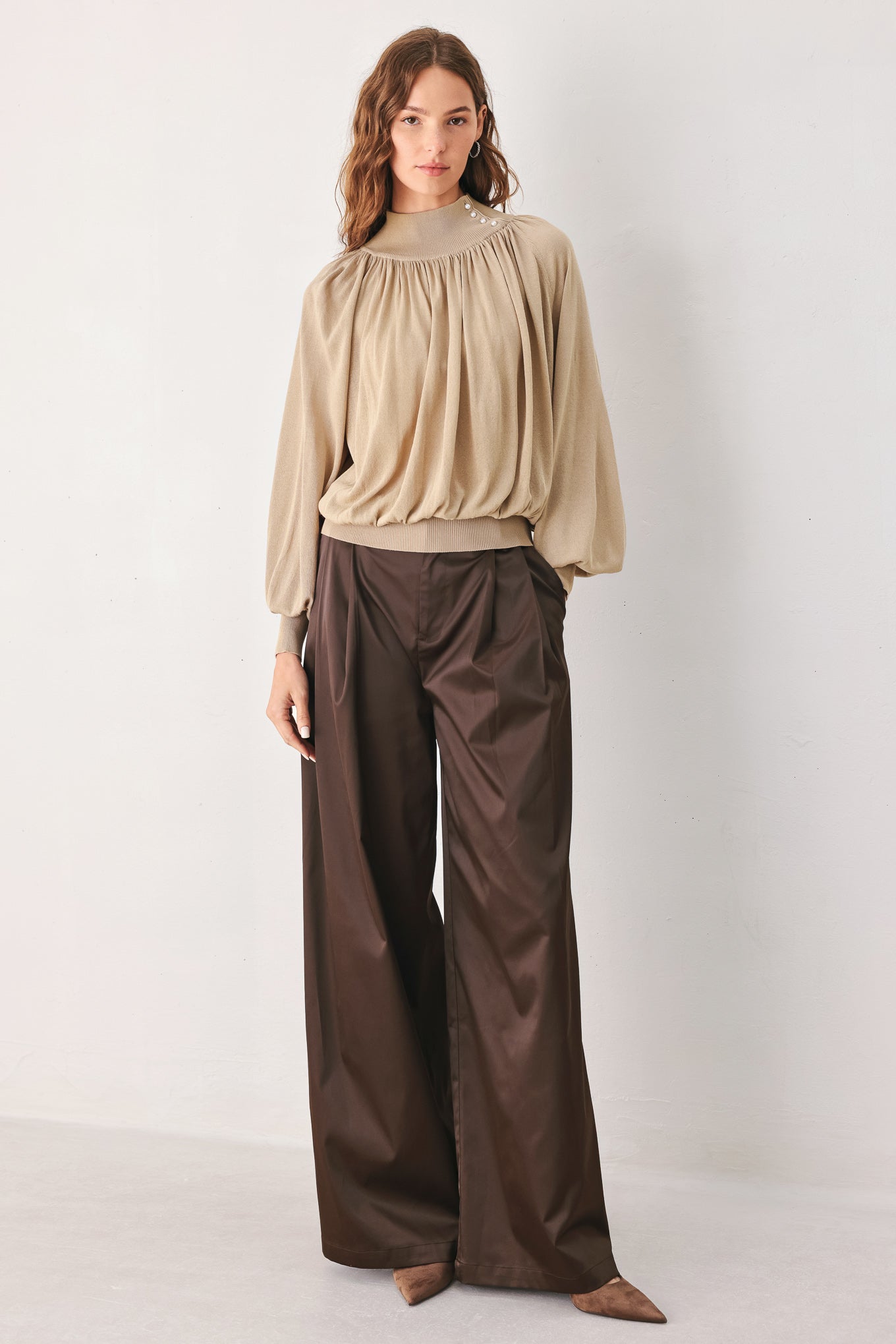 A woman wearing a taupe long-sleeve blouse with a high gathered neckline and pearl-like embellishments | FREEMARKET