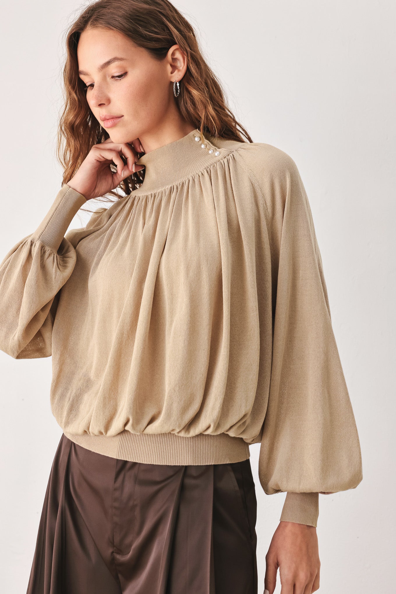 A woman wearing a taupe long-sleeve blouse with a high gathered neckline and pearl-like embellishments | FREEMARKET