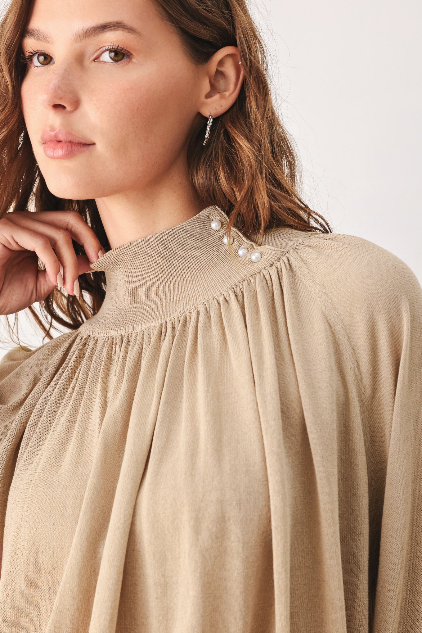 A woman wearing a taupe long-sleeve blouse with a high gathered neckline and pearl-like embellishments | FREEMARKET