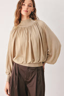 A woman wearing a taupe long-sleeve blouse with a high gathered neckline and pearl-like embellishments | FREEMARKET