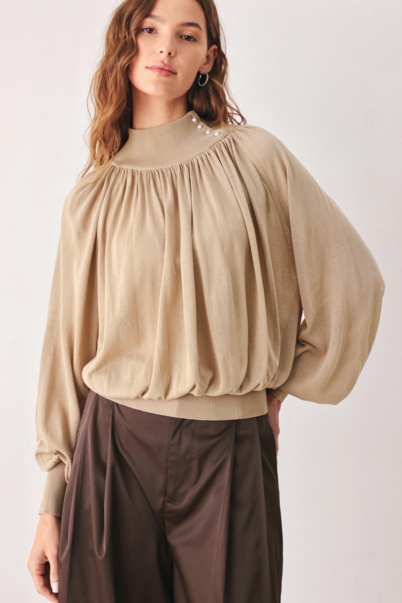A woman wearing a taupe long-sleeve blouse with a high gathered neckline and pearl-like embellishments | FREEMARKET