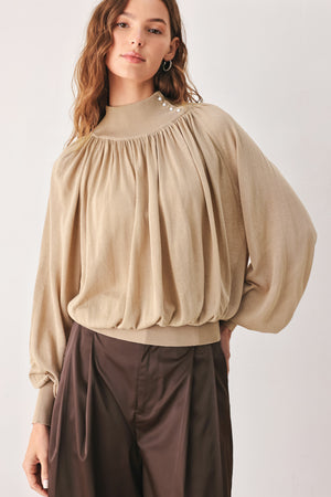 A woman wearing a taupe long-sleeve blouse with a high gathered neckline and pearl-like embellishments | FREEMARKET
