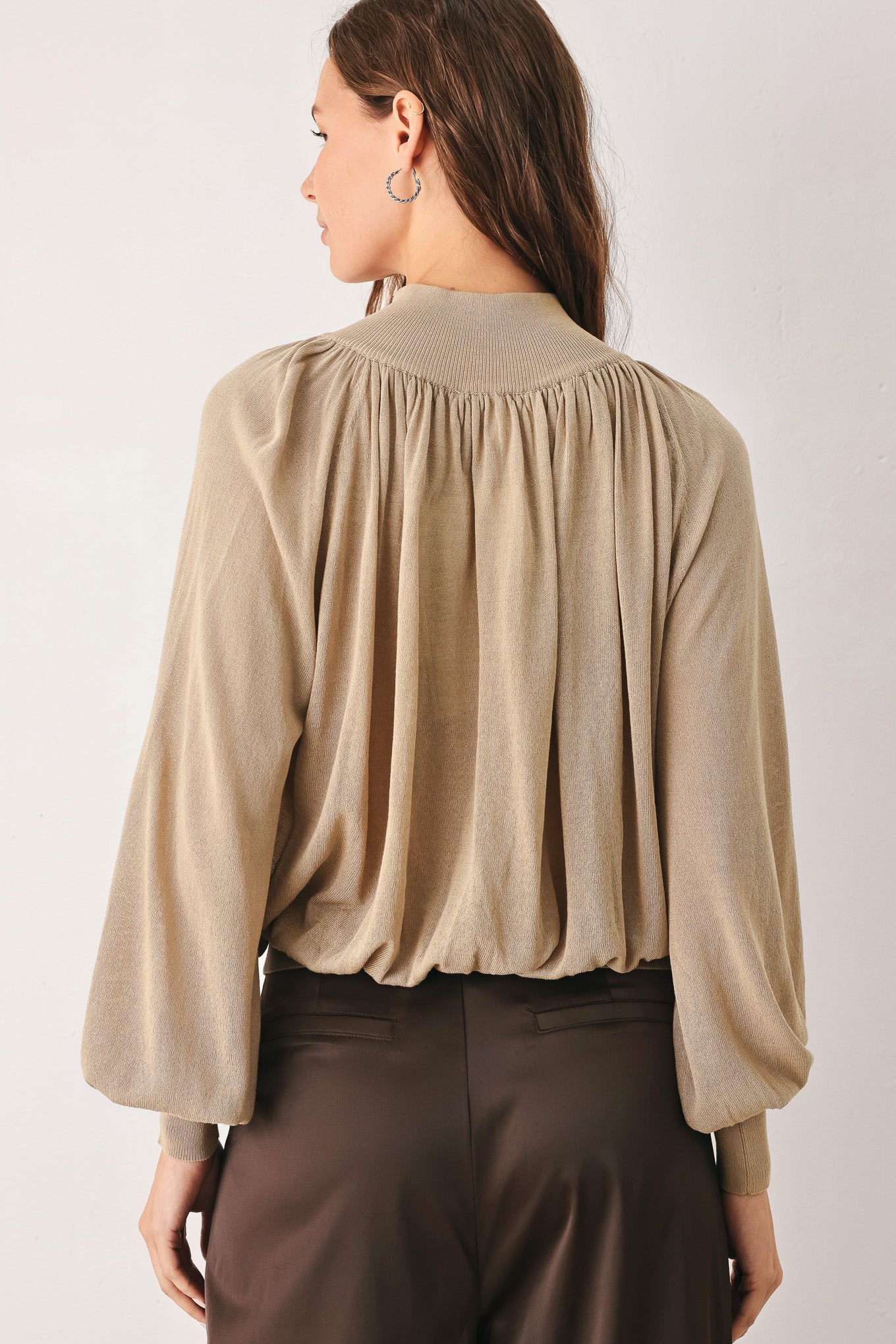 A woman wearing a taupe long-sleeve blouse with a high gathered neckline and pearl-like embellishments | FREEMARKET
