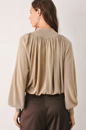 A woman wearing a taupe long-sleeve blouse with a high gathered neckline and pearl-like embellishments | FREEMARKET