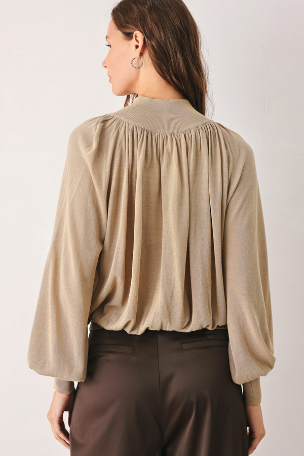 A woman wearing a taupe long-sleeve blouse with a high gathered neckline and pearl-like embellishments | FREEMARKET