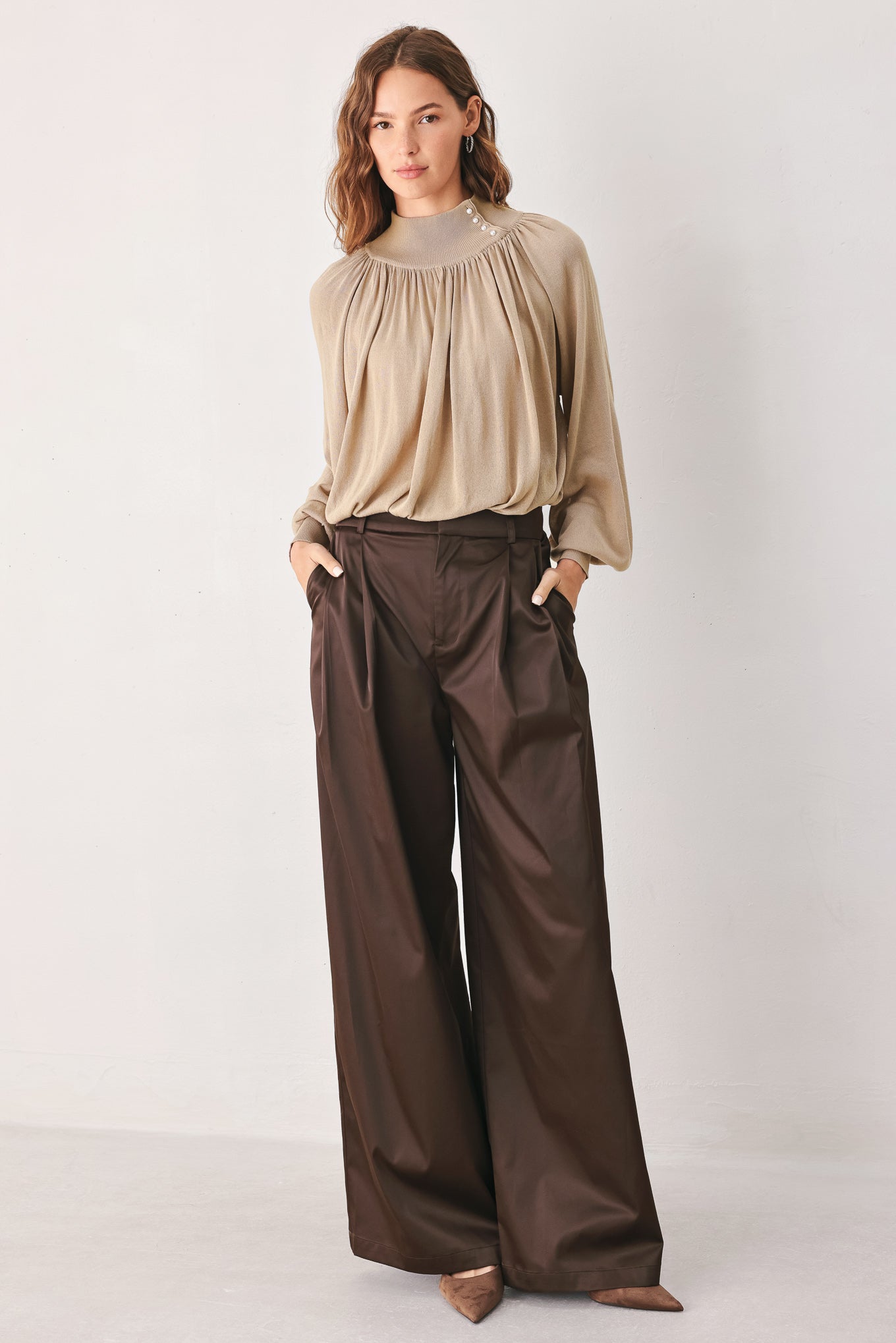 A woman wearing a taupe long-sleeve blouse with a high gathered neckline and pearl-like embellishments | FREEMARKET