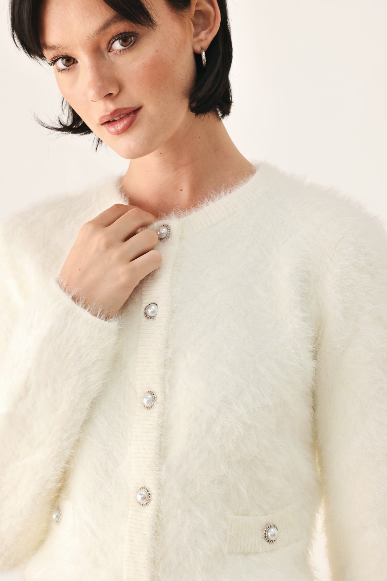 A model wearing an ivory fuzzy cropped cardigan with buttons | FREEMARKET