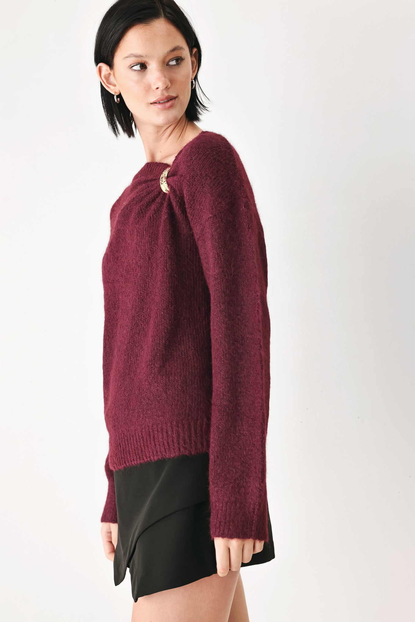 A woman modeling a dark burgundy knit sweater with a unique draped neckline and a small gold button accent | FREEMARKET