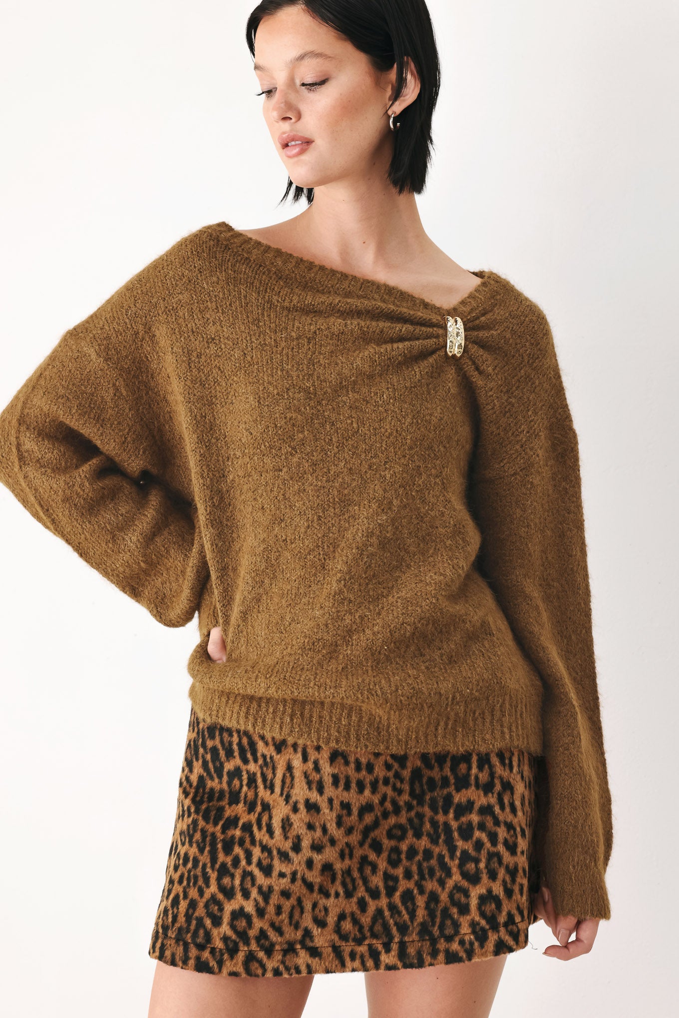 A woman modeling a camel knit sweater with a unique draped neckline and a small gold button accent | FREEMARKET