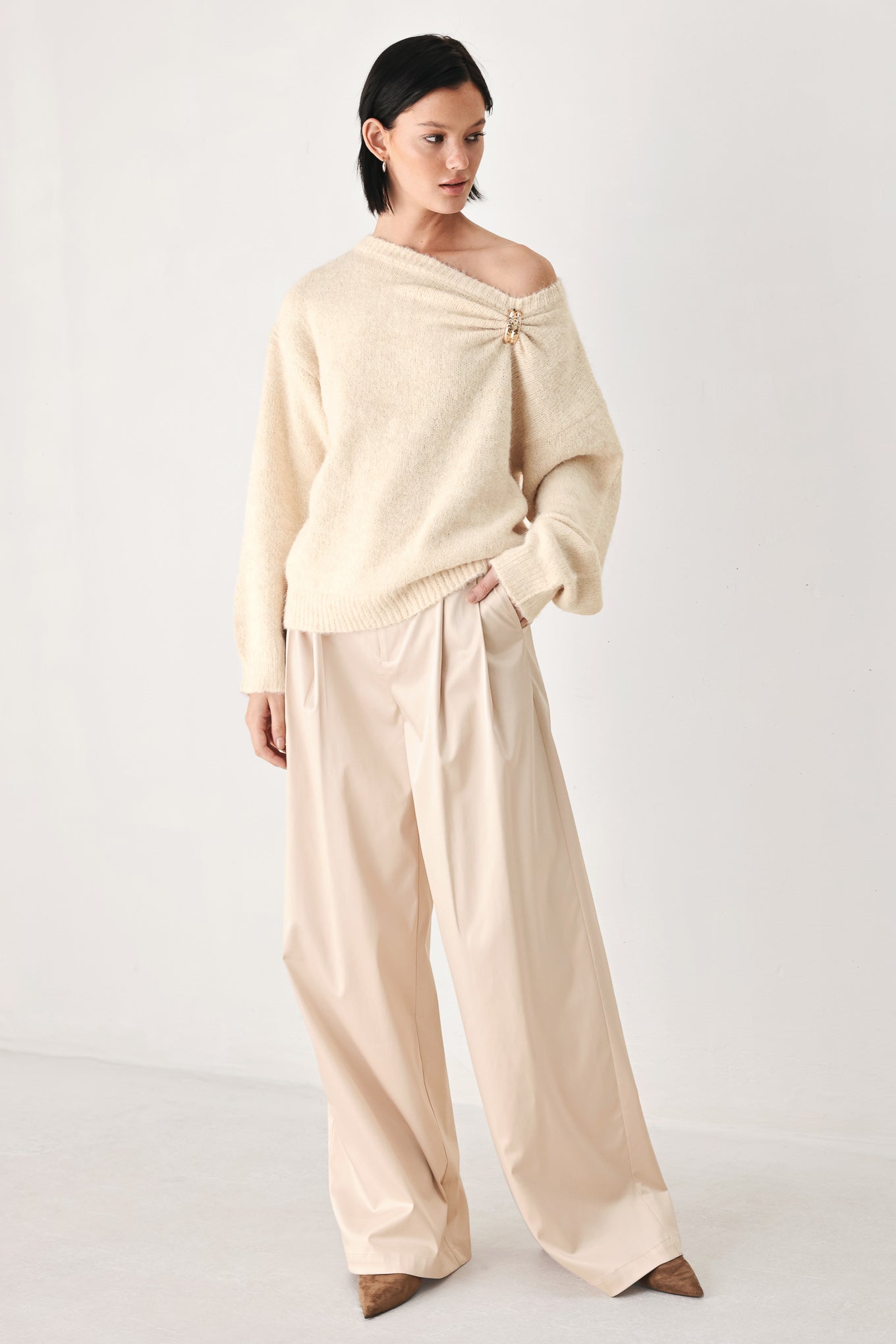A woman modeling a ivory knit sweater with a unique draped neckline and a small gold button accent | FREEMARKET