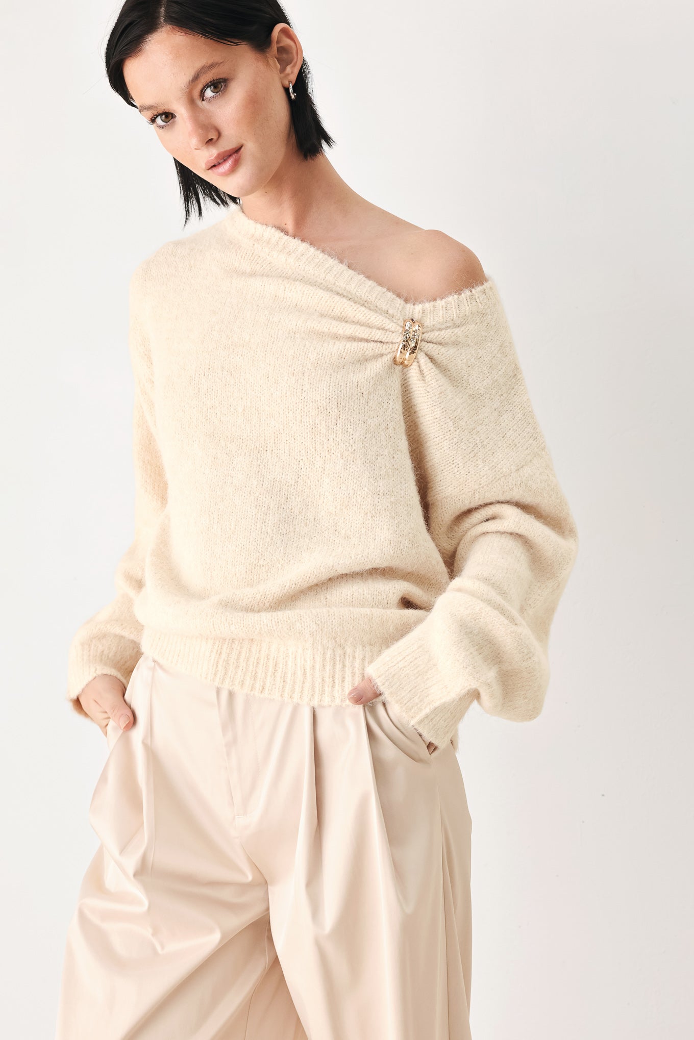 A woman modeling a ivory knit sweater with a unique draped neckline and a small gold button accent | FREEMARKET