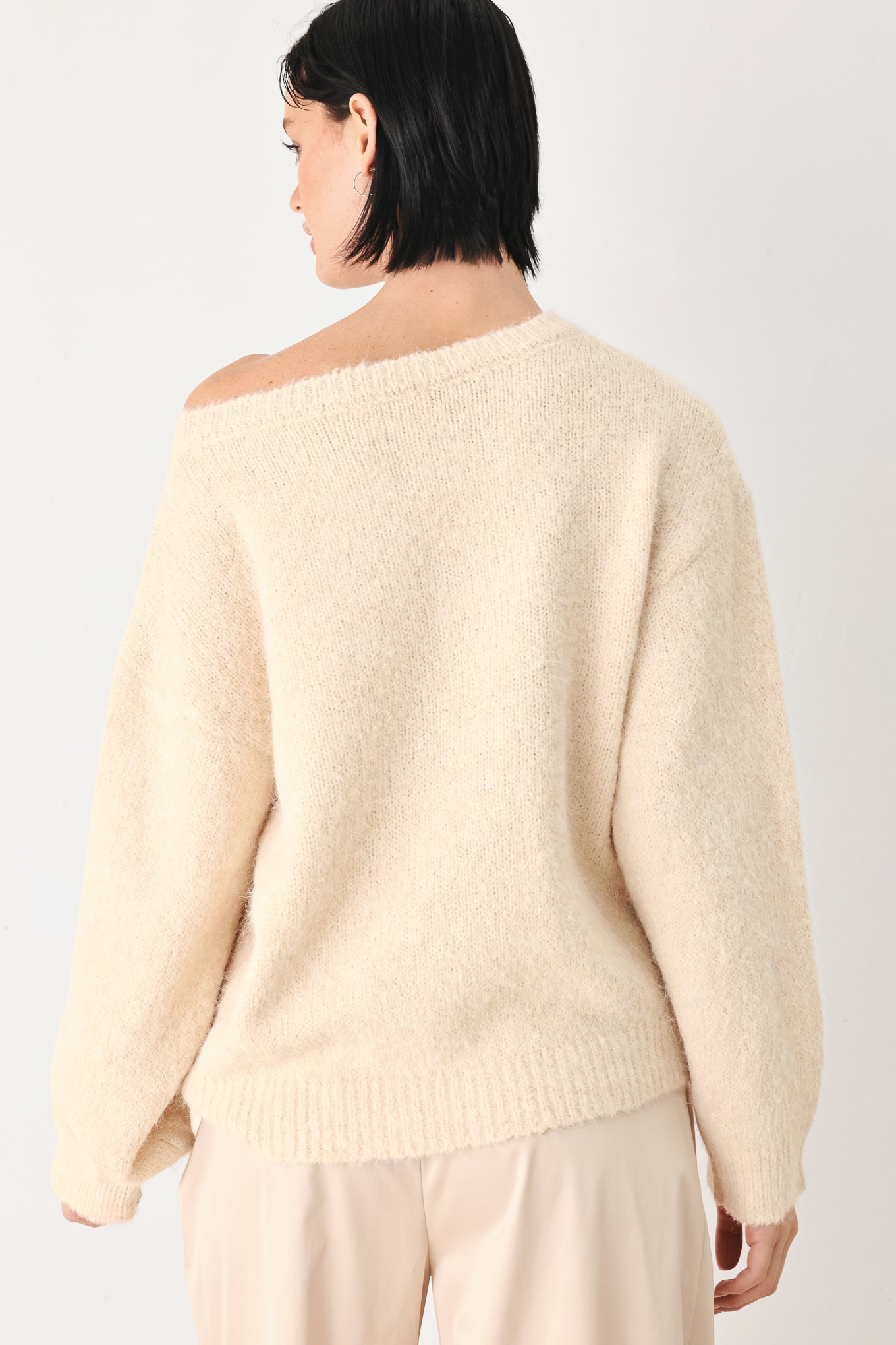A woman modeling a ivory knit sweater with a unique draped neckline and a small gold button accent | FREEMARKET
