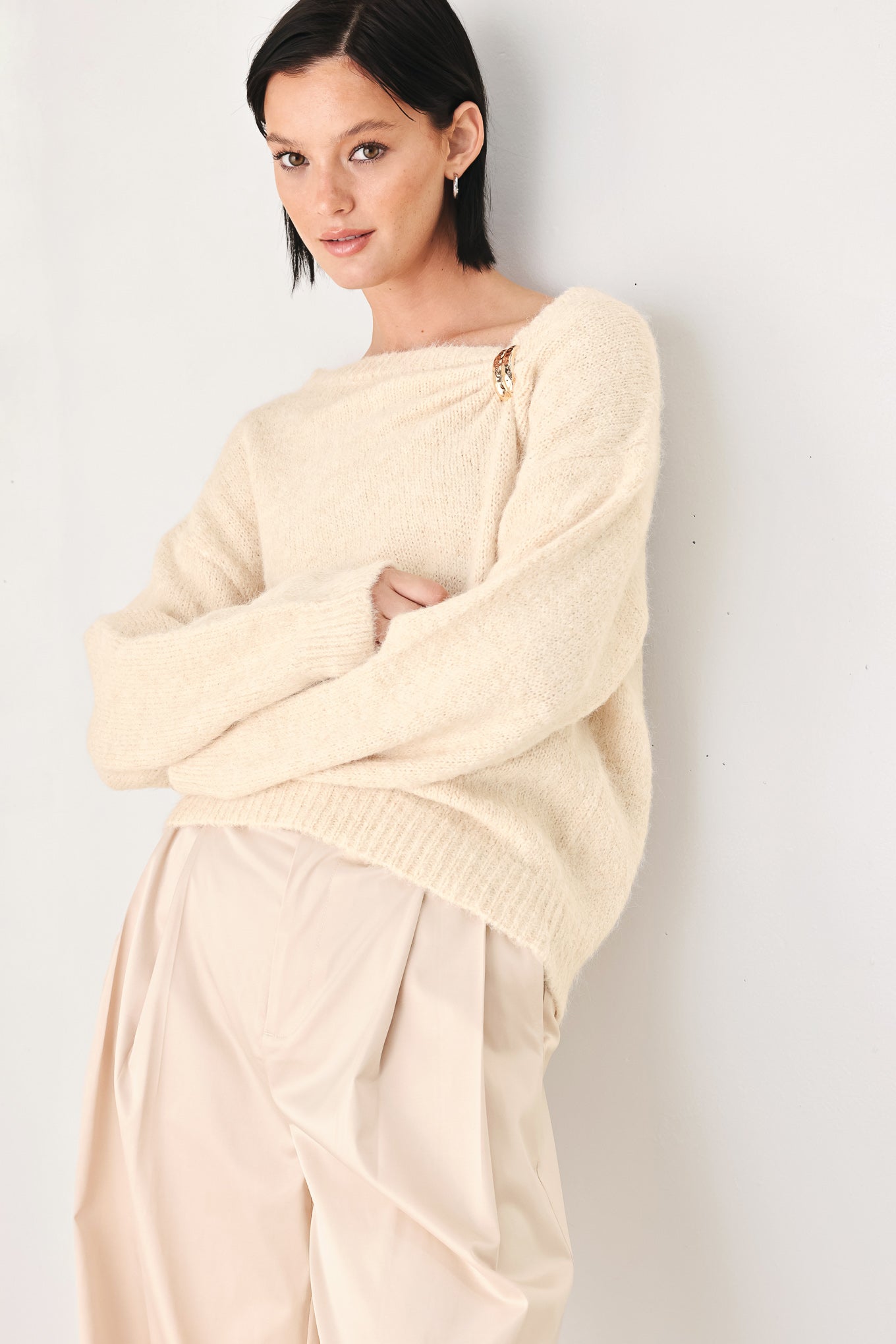 A woman modeling a ivory knit sweater with a unique draped neckline and a small gold button accent | FREEMARKET