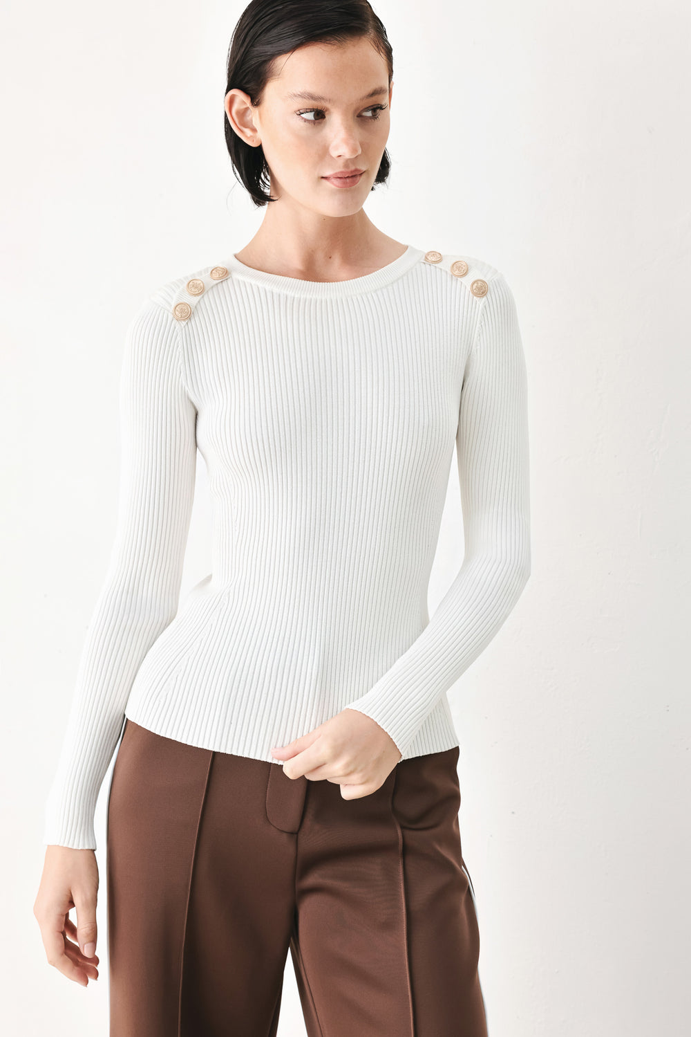A woman modeling a white ribbed long-sleeve sweater with decorative gold buttons on the shoulders | FREEMARKET
