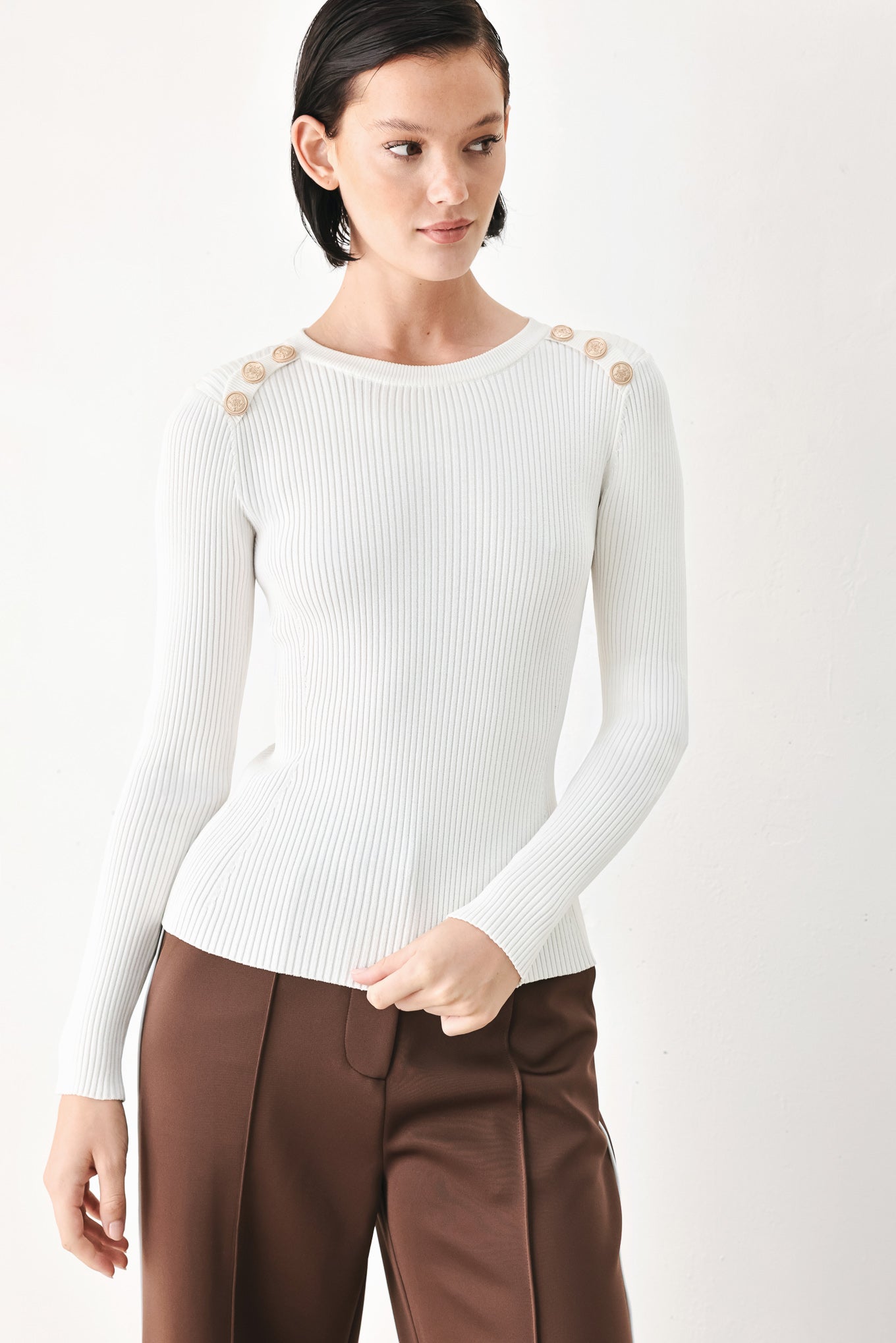 A woman modeling a white ribbed long-sleeve sweater with decorative gold buttons on the shoulders | FREEMARKET