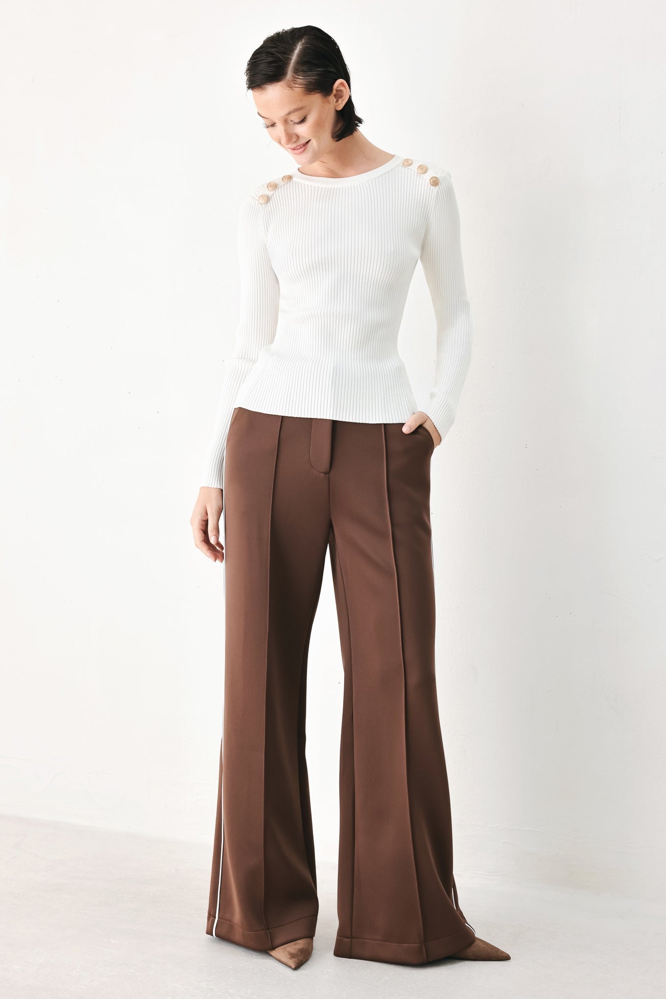 A woman modeling a white ribbed long-sleeve sweater with decorative gold buttons on the shoulders | FREEMARKET