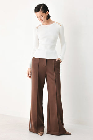A woman modeling a white ribbed long-sleeve sweater with decorative gold buttons on the shoulders | FREEMARKET